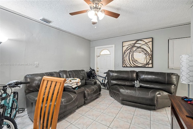 living room featuring a textured ceiling, ceiling fan, and light tile patterned floors