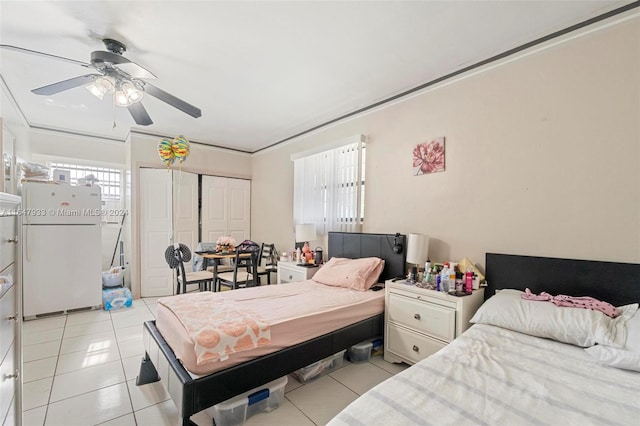 bedroom with ceiling fan, white fridge, crown molding, and light tile patterned floors