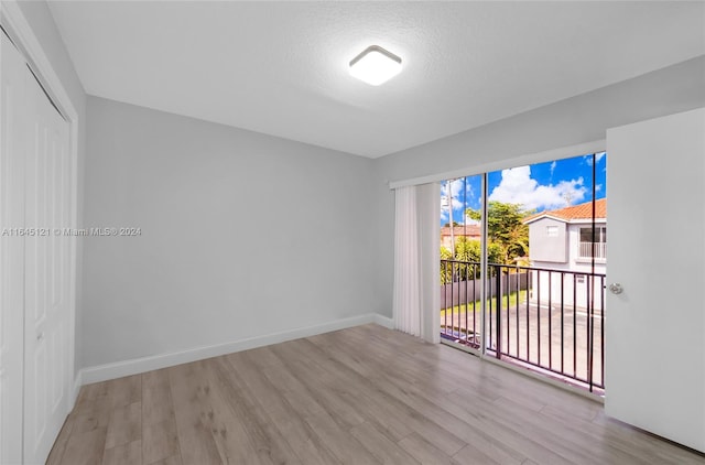 spare room with a textured ceiling and light hardwood / wood-style flooring