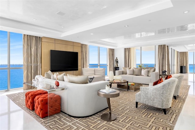 tiled living room featuring a raised ceiling and a wall of windows