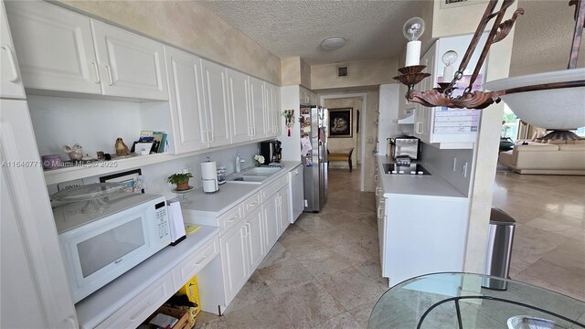 16400 Collins Ave Unit 646, Sunny Isles Beach, FL 33160 - kitchen with white appliances, light countertops, under cabinet range hood, a textured ceiling, and a chandelier