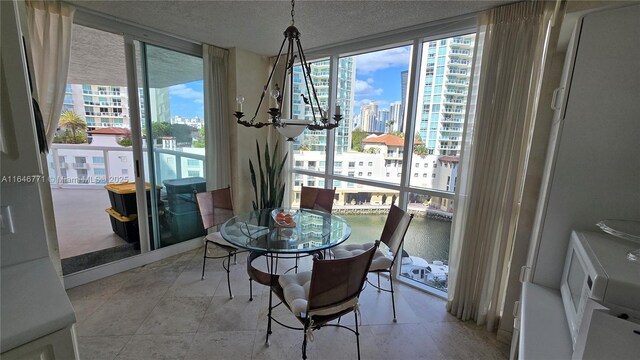 16400 Collins Ave Unit 646, Sunny Isles Beach, FL 33160 - kitchen featuring under cabinet range hood, white cabinetry, black electric cooktop, white double oven, and a chandelier