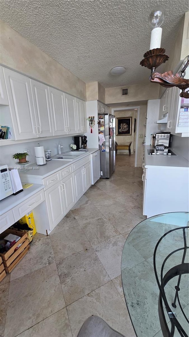 kitchen featuring sink, a textured ceiling, white cabinets, and white appliances