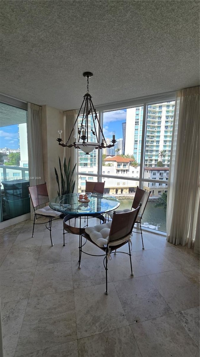 dining room with a water view, an inviting chandelier, and a textured ceiling