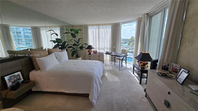 bedroom with a wall of windows, light carpet, and a textured ceiling