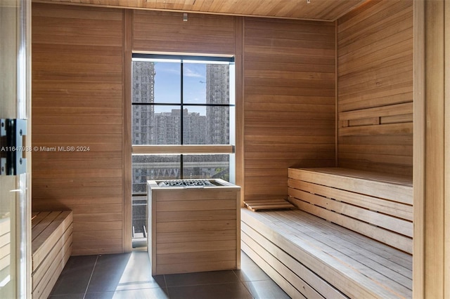 view of sauna featuring tile patterned flooring, wood ceiling, and wooden walls