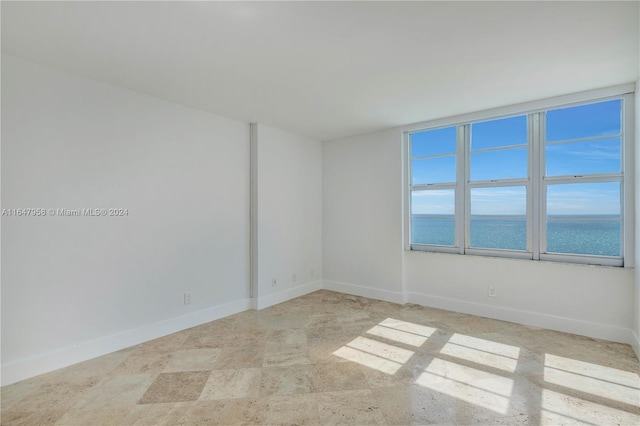 tiled spare room featuring a water view