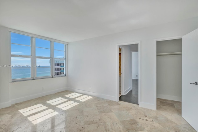 unfurnished bedroom featuring light tile patterned flooring, a closet, and a water view