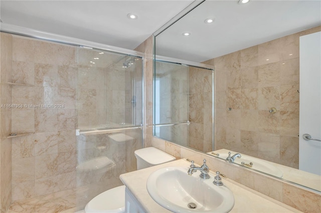 bathroom featuring vanity, toilet, a shower with shower door, and tile walls