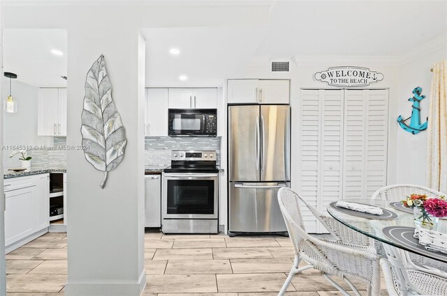 kitchen featuring decorative backsplash, white cabinets, stone countertops, crown molding, and stainless steel appliances