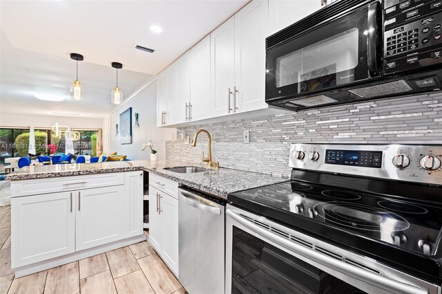 kitchen featuring sink, light stone counters, white cabinetry, stainless steel appliances, and kitchen peninsula