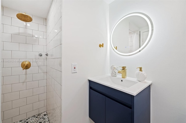 bathroom with a tile shower and vanity