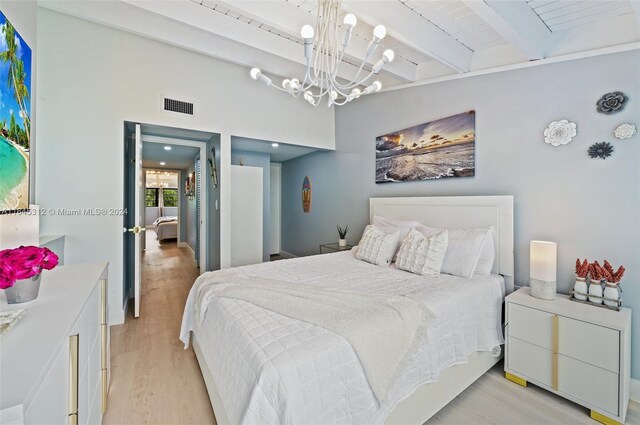 bedroom featuring beam ceiling, a chandelier, and light wood-type flooring