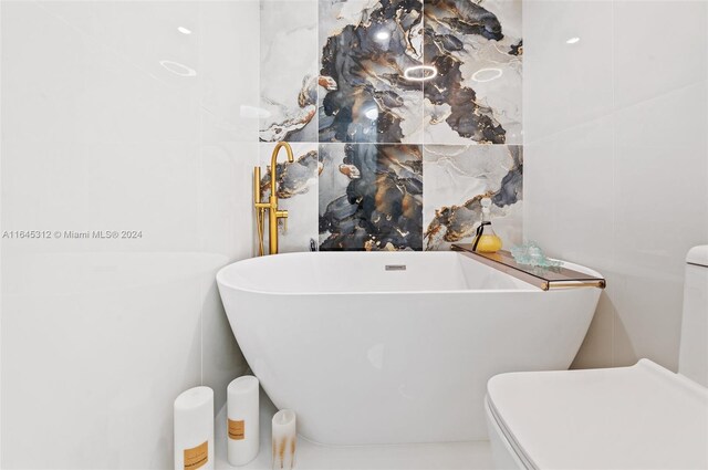 bathroom featuring toilet and a tub to relax in