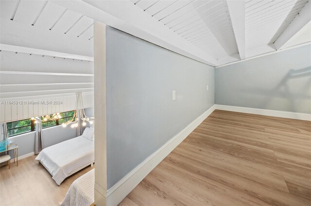 bedroom featuring lofted ceiling with beams and light hardwood / wood-style flooring