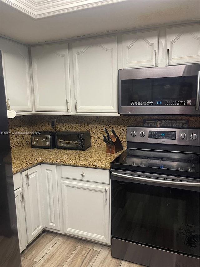 kitchen with stone counters, appliances with stainless steel finishes, light hardwood / wood-style flooring, and white cabinetry