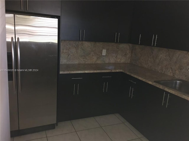 kitchen with sink, light tile patterned flooring, stone counters, and stainless steel refrigerator with ice dispenser