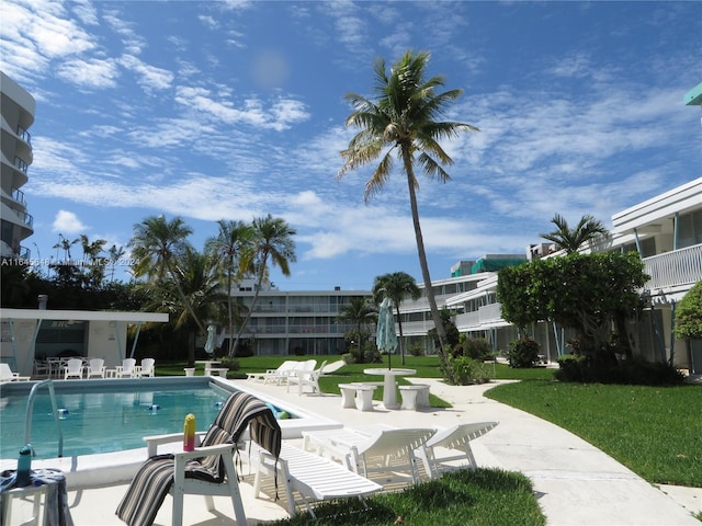 community pool with a patio area and a lawn