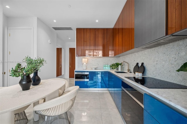 kitchen featuring tasteful backsplash, modern cabinets, black electric stovetop, light countertops, and a sink