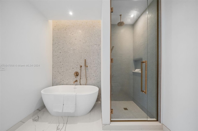 bathroom featuring a stall shower, marble finish floor, and a freestanding bath