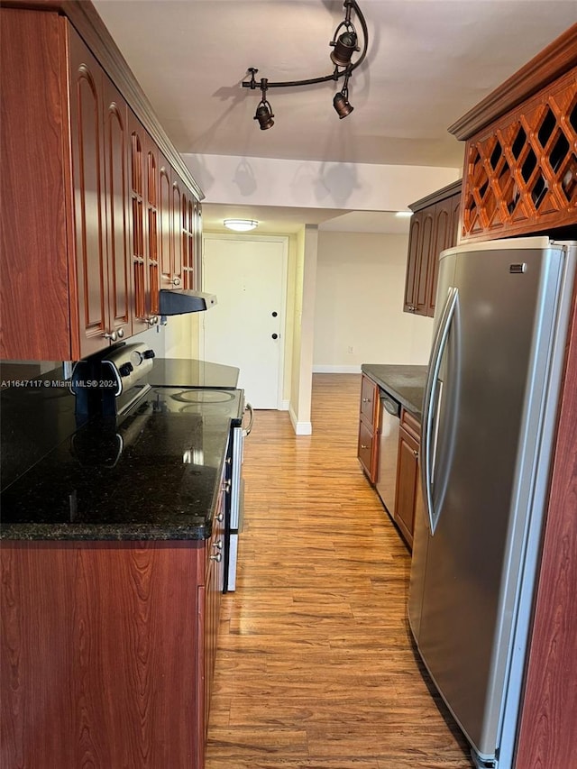 kitchen featuring dark stone countertops, range hood, stainless steel appliances, and light hardwood / wood-style flooring