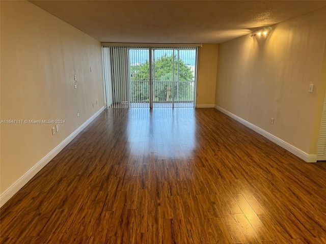 empty room with dark hardwood / wood-style floors and expansive windows