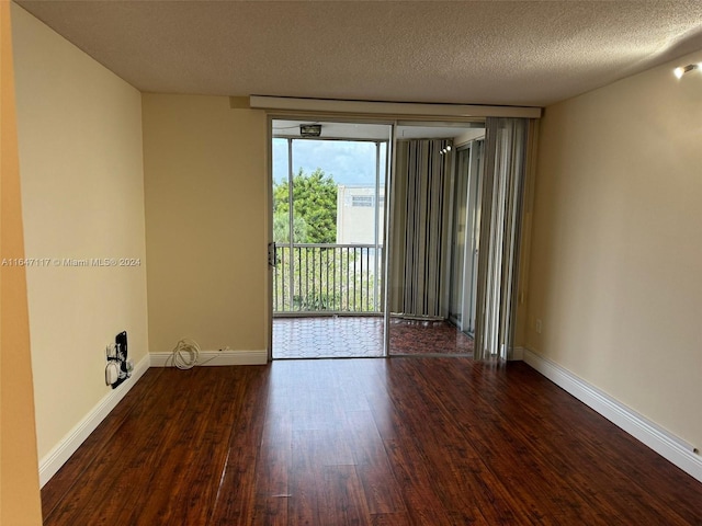 empty room with a textured ceiling and dark hardwood / wood-style flooring