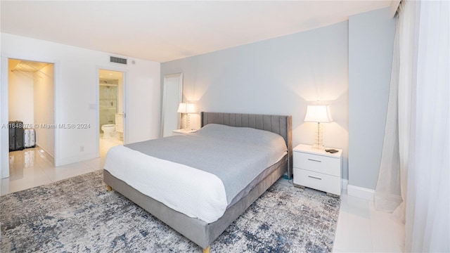 bedroom featuring a closet, ensuite bath, light tile patterned floors, and a walk in closet