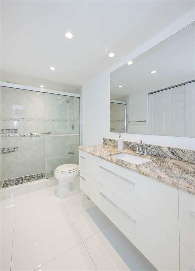 bathroom featuring vanity, toilet, tile patterned floors, and a shower with shower door