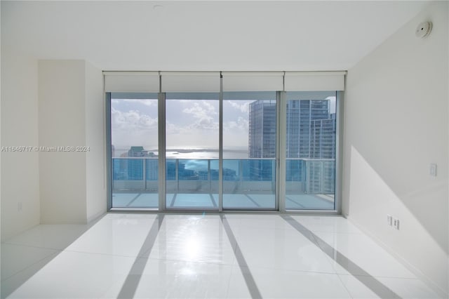 empty room featuring floor to ceiling windows and light tile patterned floors