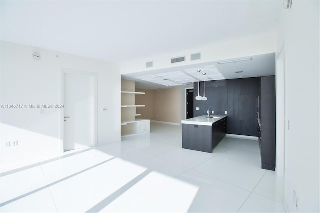 kitchen with sink, a kitchen island, light tile patterned flooring, and pendant lighting