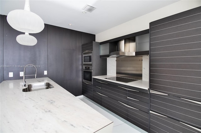 kitchen featuring appliances with stainless steel finishes, sink, wall chimney exhaust hood, decorative light fixtures, and tile patterned floors