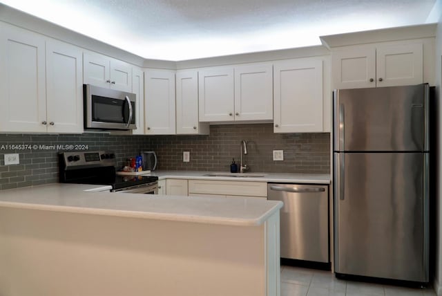 kitchen with appliances with stainless steel finishes, kitchen peninsula, sink, and tasteful backsplash