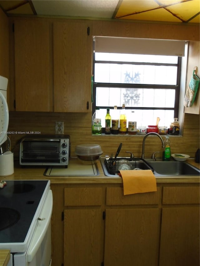 kitchen featuring plenty of natural light, white electric range, sink, and tasteful backsplash