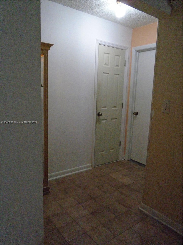 corridor with dark tile patterned floors and a textured ceiling