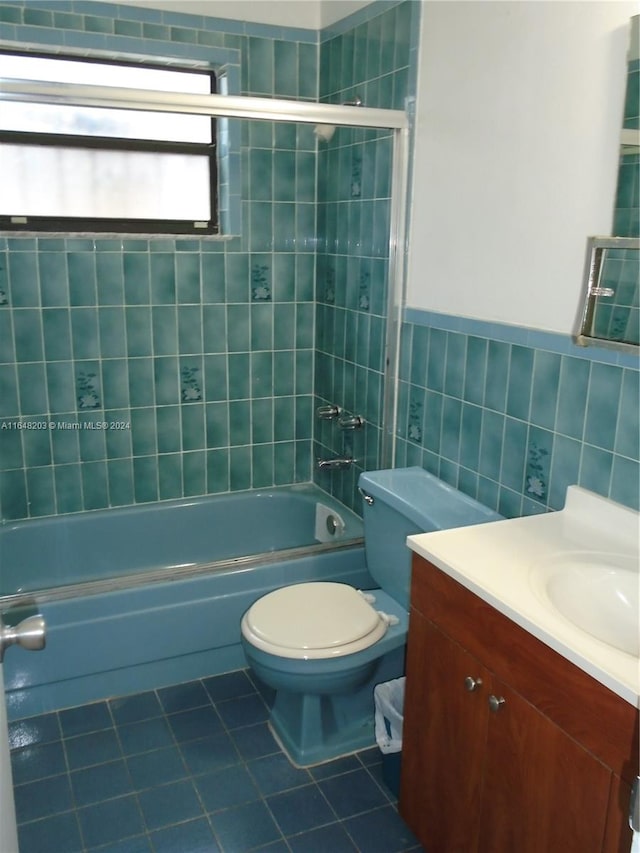 full bathroom featuring tile patterned flooring, toilet, vanity, tile walls, and tiled shower / bath