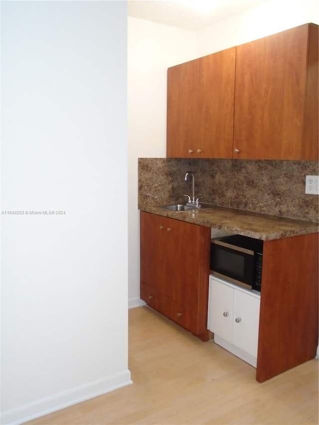 kitchen featuring light hardwood / wood-style floors, sink, and tasteful backsplash