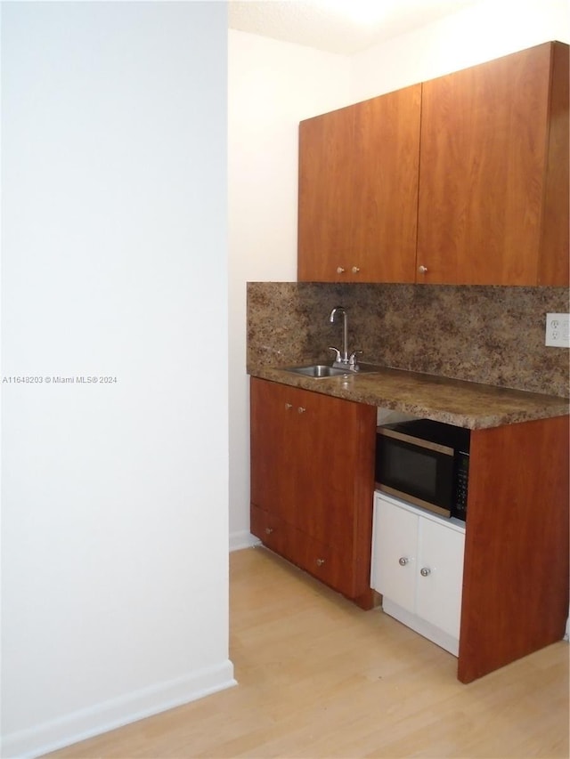 158 NW 18th Ct, Miami, FL 33125 - kitchen with black microwave, light wood-type flooring, tasteful backsplash, and brown cabinetry