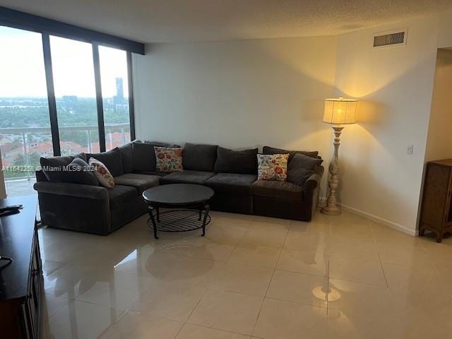 living room featuring a textured ceiling, plenty of natural light, a wall of windows, and light tile patterned flooring