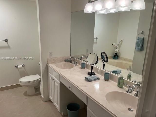 bathroom with dual bowl vanity, toilet, and tile patterned floors