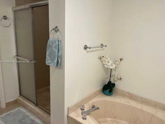 bathroom featuring a stall shower and a bath