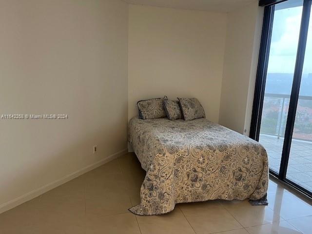 bedroom featuring multiple windows, expansive windows, light tile patterned floors, and access to outside