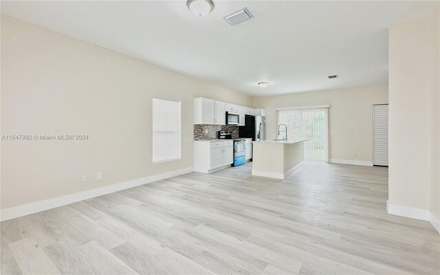 kitchen with decorative backsplash, a center island with sink, white cabinetry, light hardwood / wood-style flooring, and stainless steel appliances