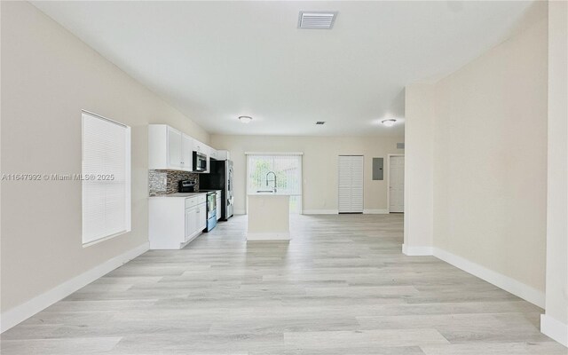 kitchen featuring appliances with stainless steel finishes, sink, backsplash, light hardwood / wood-style floors, and white cabinets