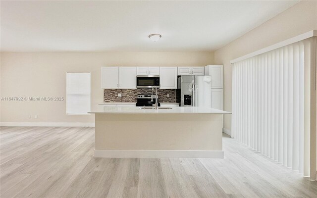 kitchen with white cabinets, stainless steel appliances, sink, and an island with sink