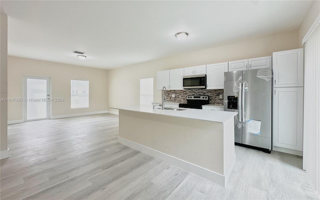 kitchen featuring decorative backsplash, an island with sink, white cabinetry, appliances with stainless steel finishes, and light hardwood / wood-style floors