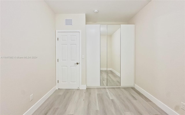 unfurnished bedroom with a closet and light hardwood / wood-style floors