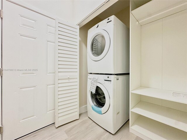 clothes washing area with stacked washing maching and dryer and light hardwood / wood-style floors