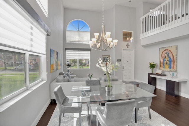 dining space with dark hardwood / wood-style flooring, an inviting chandelier, and a high ceiling