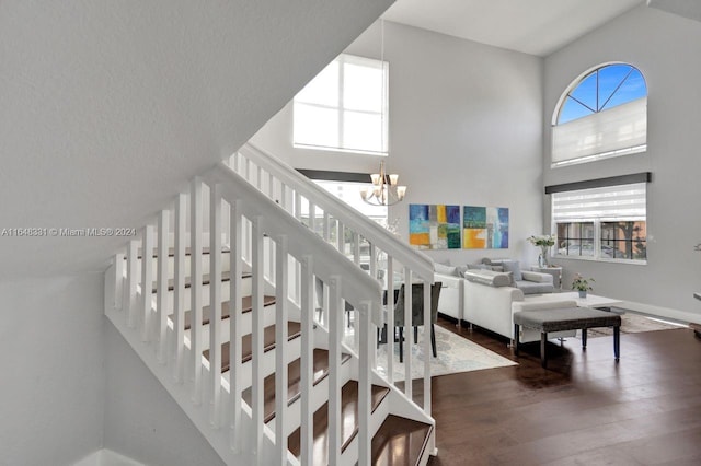 staircase with hardwood / wood-style flooring, plenty of natural light, and a notable chandelier